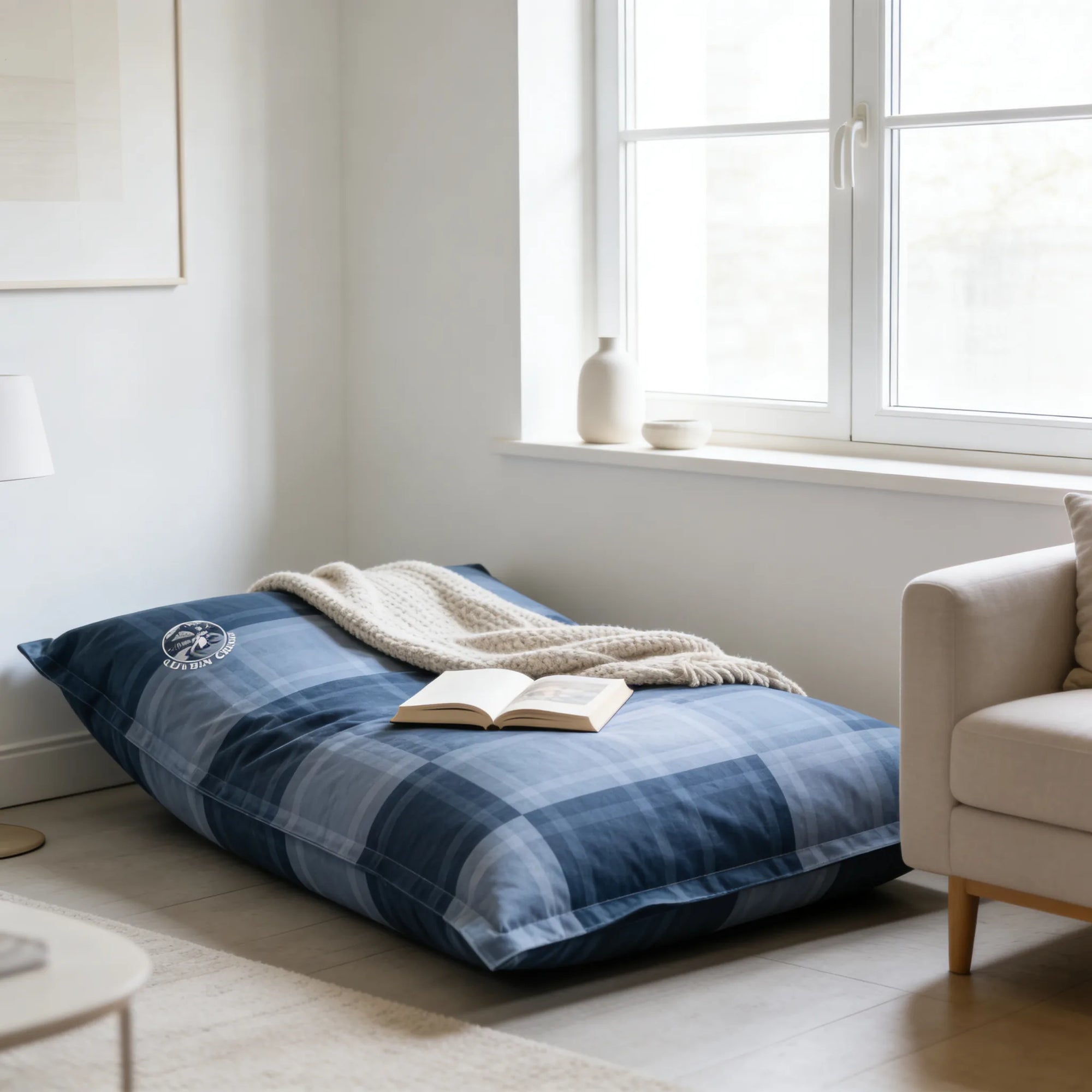 Bean bag Osmoze dans un salon lumineux avec un livre et un plaid